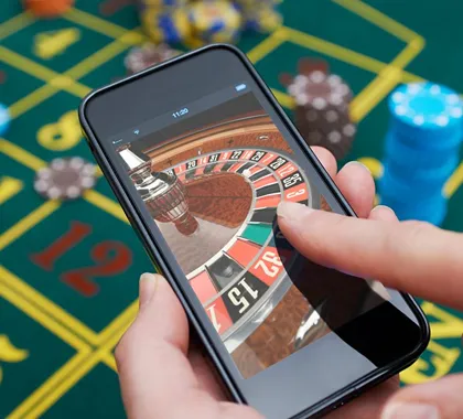 A hand holding a smartphone displaying a mobile live roulette game on the screen